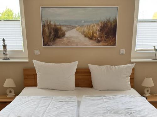 a bedroom with a bed with white pillows and a painting at Villa Ostseebrise in Trent