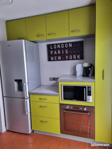 La cuisine est équipée de placards jaunes et d'un réfrigérateur blanc. dans l'établissement Maison bord de plage, à Saint-Hilaire-de-Riez