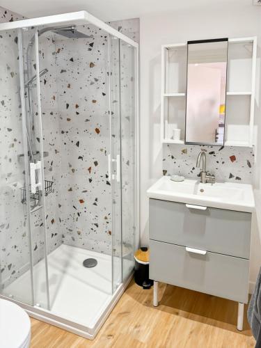 une salle de bain blanche avec une douche et un lavabo dans l'établissement Charmant Studio au Cœur d'Aurillac La belle Verte, à Aurillac