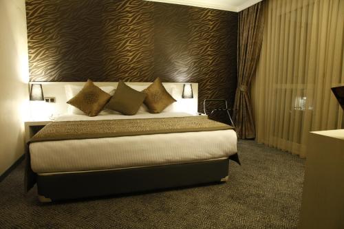 a bedroom with a large bed with pillows on it at Koza Suite Hotel in Ankara