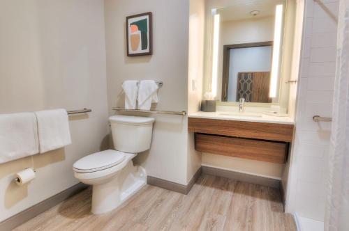 a bathroom with a toilet and a sink and a mirror at Holiday Inn Gainesville-University Center by IHG in Gainesville