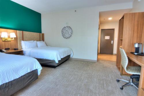 a hotel room with two beds and a desk at Holiday Inn Gainesville-University Center by IHG in Gainesville