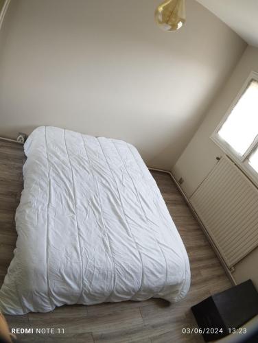 un lit blanc dans une chambre avec une fenêtre dans l'établissement Maison à 5' du circuit du Mans, à Mulsanne