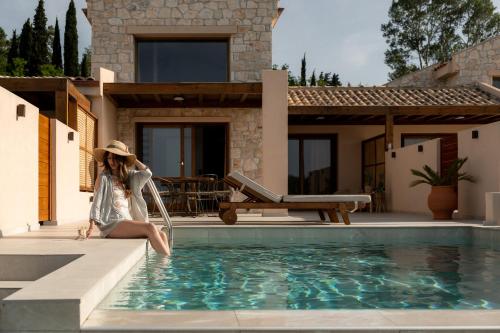 a woman sitting on the edge of a swimming pool at Candelas Suites & Nature in Ierissos