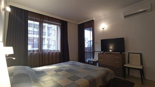 a bedroom with a bed and a television and a dresser at Premium Oasis Beach Club Apartment in Lozenets