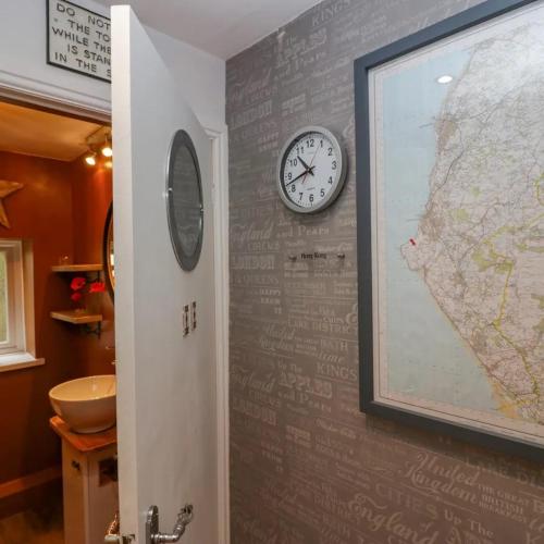 a wall with a clock and a map on it at Tranquil Lake District Village Apartment in St Bees