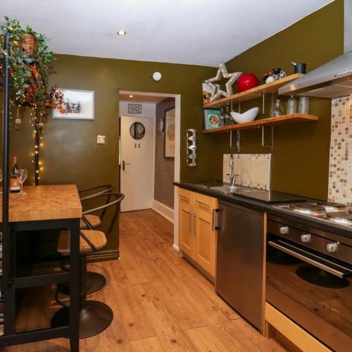 a kitchen with green walls and a counter top at Tranquil Lake District Village Apartment in St Bees