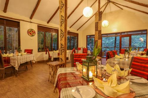 a restaurant with tables and chairs in a room at Gorilla Safari Lodge in Rubuguli