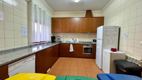 a kitchen with wooden cabinets and a white refrigerator at Raízes da Vinha - Quartos & Chalé na Serra da Estrela in Carragozela