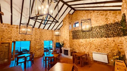 a dining room with wooden tables and chairs and chandeliers at Raízes da Vinha - Quartos & Chalé na Serra da Estrela in Carragozela