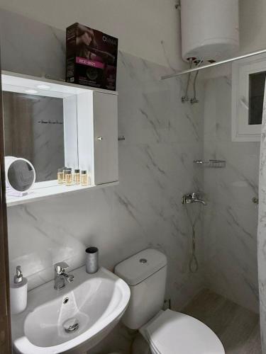 a white bathroom with a toilet and a sink at Rozy Studios in Pefki