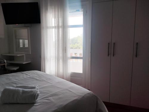 a white bedroom with a bed and a window at Tarmaros - Families & Groups in Sissi