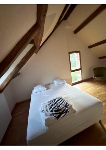 une chambre avec un lit blanc dans un grenier dans l'établissement GITES LUXE GETAWAY CAMPAGNE Sologne, à Souesmes