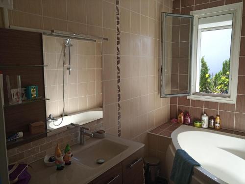 une salle de bain avec une baignoire, un lavabo et une fenêtre dans l'établissement Maison St Jean de Védas centre, à Saint-Jean-de-Védas