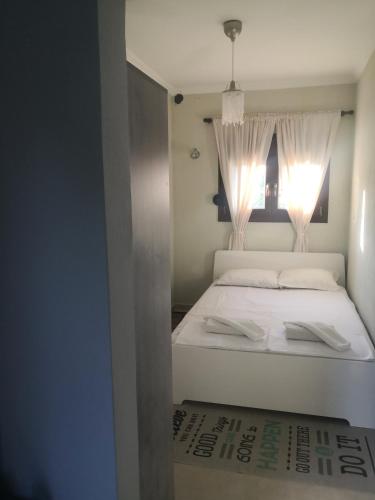 a bedroom with a white bed with a window at Anastasia in Leptokarya