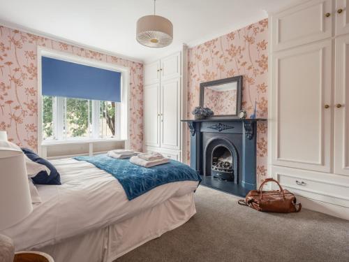 a bedroom with a large bed and a fireplace at Westhill House in Warkworth