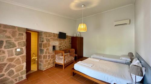 a bedroom with a bed and a stone wall at Raízes da Vinha - Quartos & Chalé na Serra da Estrela in Carragozela