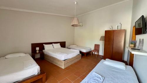 a bedroom with two beds and a table and a chair at Raízes da Vinha - Quartos & Chalé na Serra da Estrela in Carragozela
