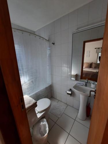 a bathroom with a toilet and a sink and a mirror at Edificio Guadalauquen in Valdivia