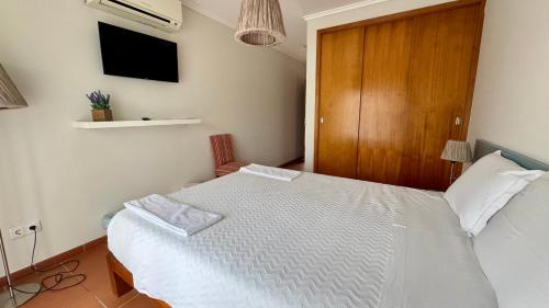 a bedroom with a white bed and a wooden cabinet at Raízes da Vinha - Quartos & Chalé na Serra da Estrela in Carragozela