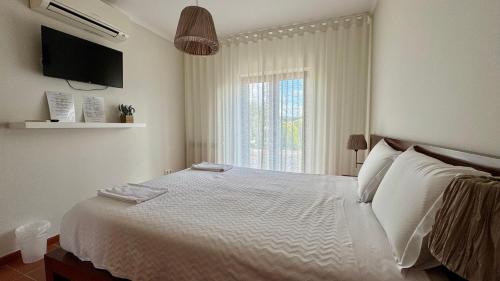 a bedroom with a large white bed with a window at Raízes da Vinha - Quartos & Chalé na Serra da Estrela in Carragozela