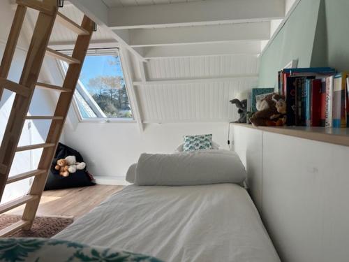 une chambre avec un lit, une échelle et des livres dans l'établissement Belle maison familiale vue sur mer, accès direct à la plage, à Pleumeur-Bodou