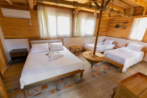 two beds in a room with wooden walls and windows at Mistral Alaçatı Hotel in Çeşme