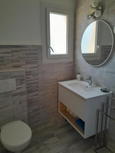 a bathroom with a sink and a toilet and a mirror at Bel appartement climatisé avec balcon 200m de la Plage in Narbonne-Plage