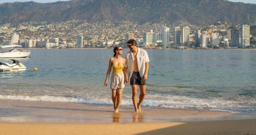 a man and a woman walking on the beach at Park Royal Beach Acapulco - All Inclusive in Acapulco