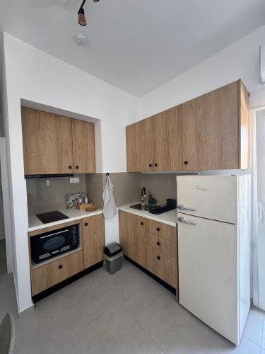 a kitchen with wooden cabinets and a white refrigerator at Creta Apt Mela Β5 in Thérissos
