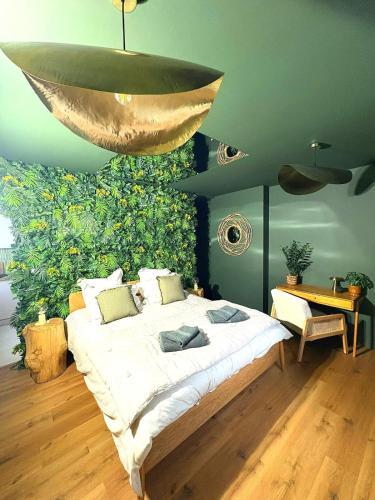 - une chambre avec un grand lit et un lustre en or dans l'établissement La Cachette Sauvage au cœur de Villefranche, à Villefranche-sur-Saône