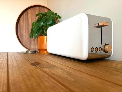 a toaster sitting on a wooden floor with a plant at La Cachette Sauvage au cœur de Villefranche in Villefranche-sur-Saône
