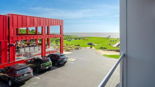 a red building with cars parked in a parking lot next to the beach at Rodanthe Pier - 2-Bedroom, 2-Bathroom Suite at REAL Watersports in Waves