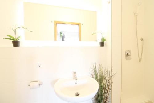 a white bathroom with a sink and a mirror at Downtown Apartments Ulm - im Herzen von Ulm & komfortable Boxspringbetten in Ulm