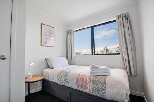 a small bedroom with a bed and a window at Modern minimalistic apartment,3BR in Auckland
