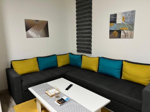 a living room with a black couch with yellow and blue cushions at Apartment Grey Deluxe in Sarajevo