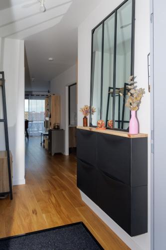 un salon avec une commode noire avec un vase dessus dans l'établissement La Parenthèse Sablaise, à Les Sables-dʼOlonne