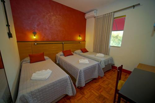 a hotel room with two beds and a window at Hotel Euro Suite Poços de Caldas By Nacional Inn in Poços de Caldas