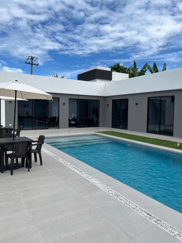 a house with a swimming pool with a table and an umbrella at Mint House Escape in Ricaurte