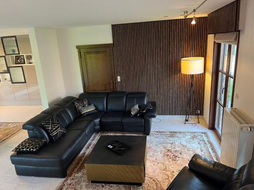 a living room with a black leather couch and a table at Luxe Villa Lou & Hans in Aalst
