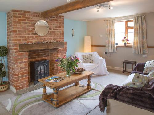 a living room with a brick fireplace and a table at Old Dairy - Ukc3169 in Walpole