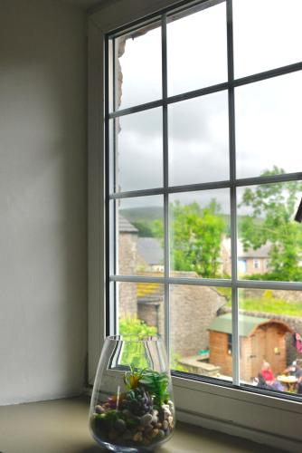 a window with a glass vase with plants in it at Muddy Boots-Arcade Royale in Kirkby Stephen
