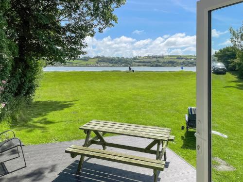 a picnic table sitting on a porch with a view of a field at Ponderosa in Llanstephan