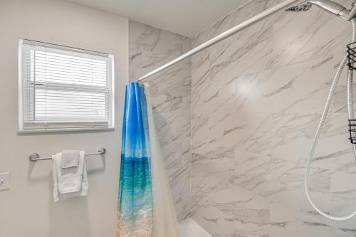 a bathroom with a shower with a blue shower curtain at Game Room, Private Pool South Daytona Home! in South Daytona