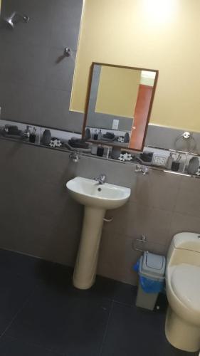 a bathroom with a sink and a toilet and a mirror at Hotel Samay Wasi in Tacna