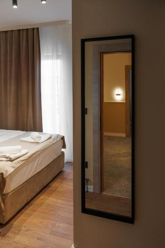 a mirror on a wall in a bedroom with a bed at Garni Hotel Maggitti in Velika Plana
