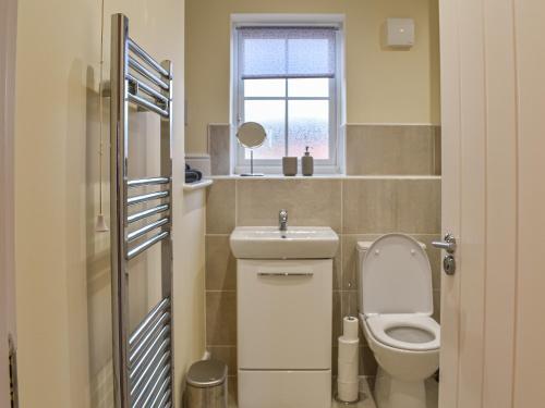 a bathroom with a toilet and a sink and a window at The Garth in Helmsley
