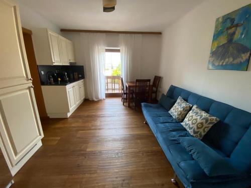 a living room with a blue couch and a kitchen at Landhaus Marmorata FeWo in Sattendorf