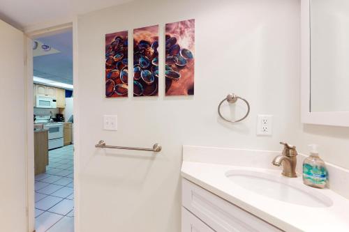 a white bathroom with a sink and three paintings on the wall at Sea Colony - 107 Brandywine House Rd in Bethany Beach
