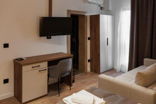 a living room with a couch and a desk with a television at Garni Hotel Maggitti in Velika Plana